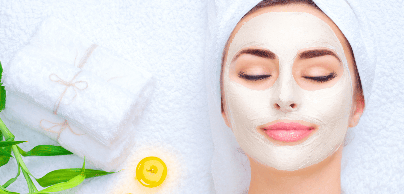Woman resting with a white towel wrapped around her head during a facial skincare treatment